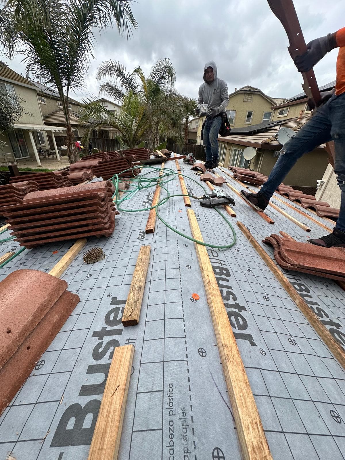 Crew installing clay tile over GAF FeltBuster underlayment