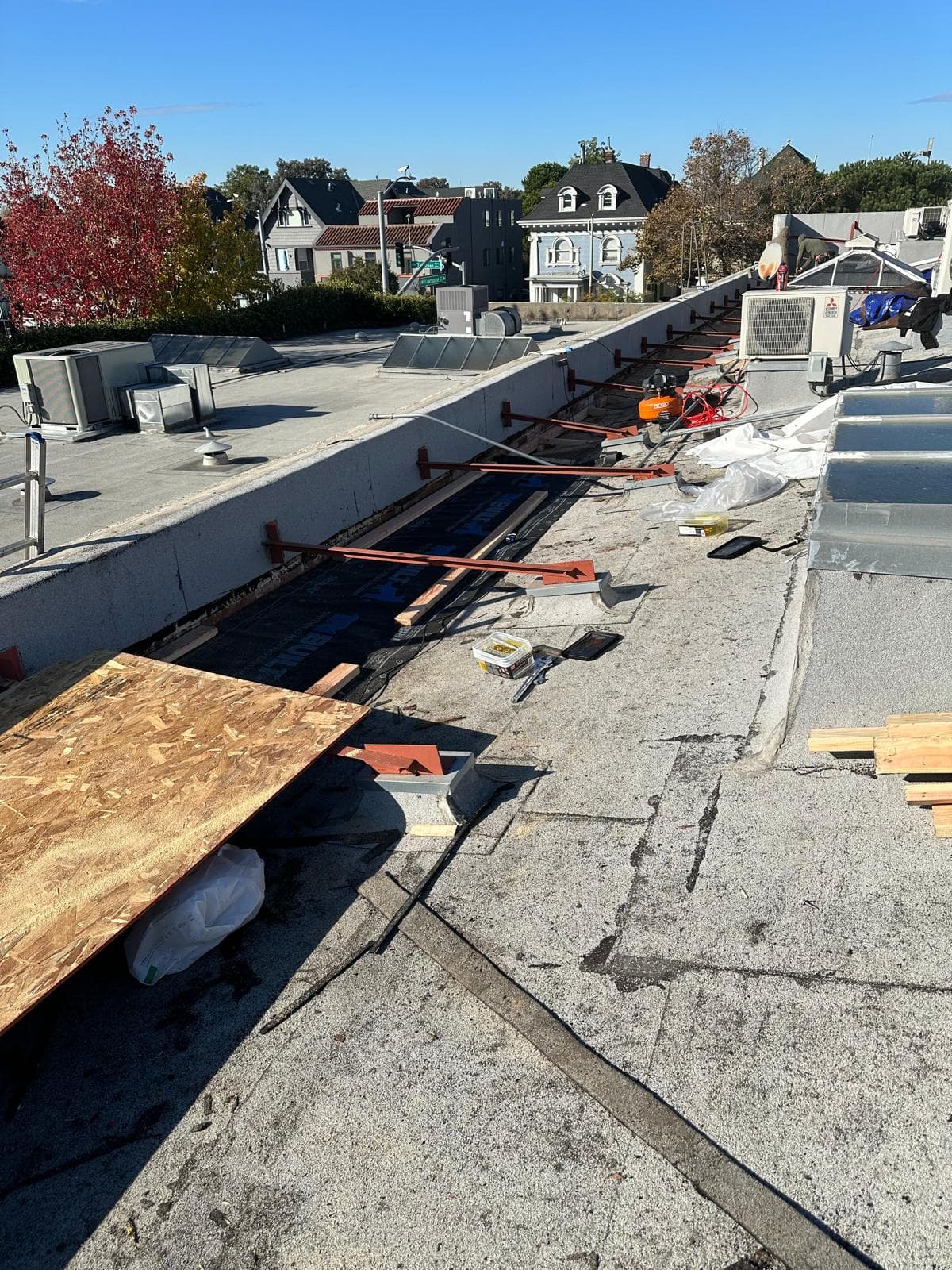Urban flat roof work with HVAC units and underlayment staged